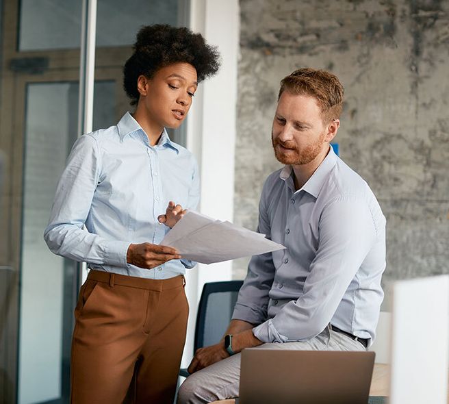 A smiling man in a navy suit, arms crossed in a bright modern workspace, conveying forward-thinking leadership.
